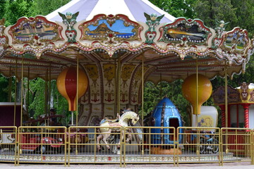 A vintage carousel with ornate decorations, featuring painted panels of scenic landscapes....