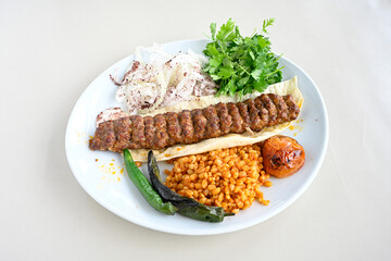Grilled Turkish Adana, Urfa  Kebab with grilled vegetables, onion and rice on plate. Urfa, Adana durum.
