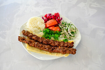 Grilled Turkish Adana, Urfa  Kebab with grilled vegetables, onion and rice on plate. Urfa, Adana durum.
