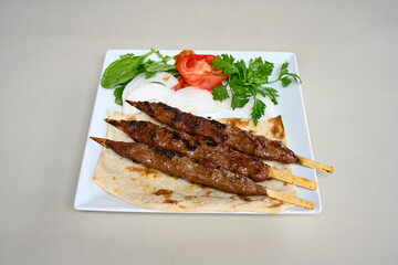 Grilled Turkish Adana, Urfa  Kebab with grilled vegetables, onion and rice on plate. Urfa, Adana durum.
