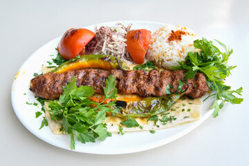 Grilled Turkish Adana, Urfa  Kebab with grilled vegetables, onion and rice on plate. Urfa, Adana durum.
