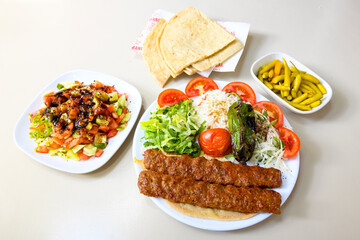 Grilled Turkish Adana, Urfa  Kebab with grilled vegetables, onion and rice on plate. Urfa, Adana durum.
