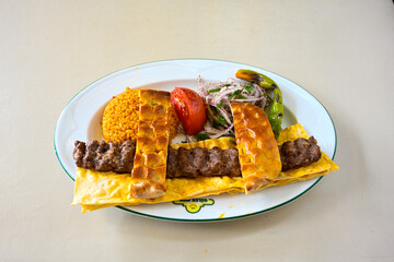 Grilled Turkish Adana, Urfa  Kebab with grilled vegetables, onion and rice on plate. Urfa, Adana durum.
