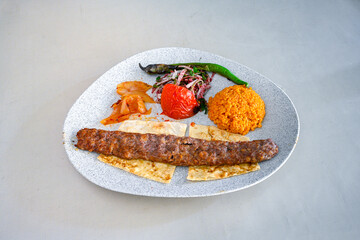 Grilled Turkish Adana, Urfa  Kebab with grilled vegetables, onion and rice on plate. Urfa, Adana durum.
