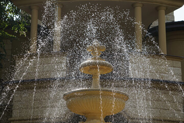 A splashing fountain on the background of a gazebo with columns on a summer day.