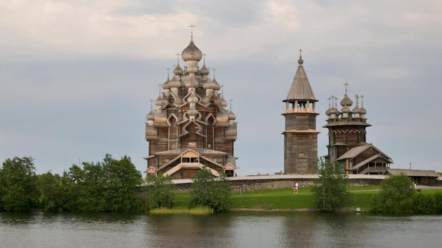 Kizhi Pogost. A historical site dating from the 17th century on Kizhi island. Russian wooden churches stand on a small island. Sunny weather. People walking are visible.
