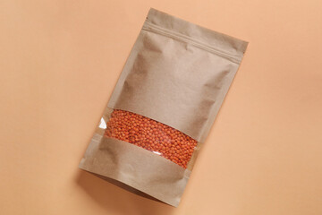 Paper pouch bag with lentil on color background, top view