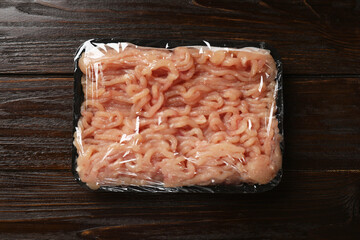 Plastic pack with fresh minced meat on wooden table, top view