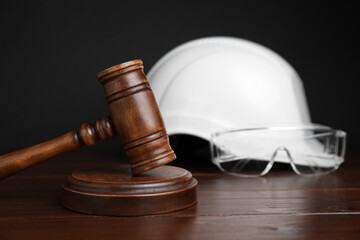 Accident at work concept. Gavel and construction worker's protective gear on wooden table,...