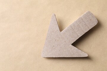 One paper arrow on kraft background, top view. Space for text