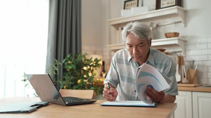 Senior business man with casual cloth looking at financial chart at home while working on laptop and making decision. Manager sitting at home while writing at document and planning strategy. Myrmidon. - Powered by Adobe