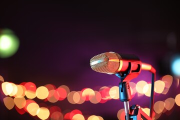 Obraz premium Microphone on stand against dark background with blurred lights, space for text. Bokeh effect