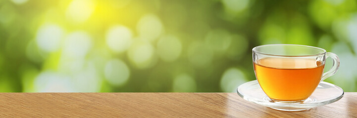 Green tea in cup on wooden table outdoors. Banner design with space for text