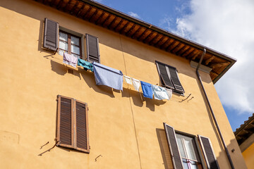 Clothes hanging outside Italy house background. Linens dry on strings on fresh air. Laundry for drying is hung on the facade of an old building. High quality photo