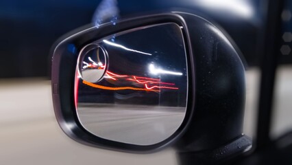 Car mirror and window reflection while driving at night. Long exposure from the car on highway. Driving at night city with bright lights and traffic. Fast moving.