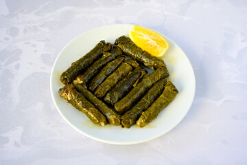 Delicious dolma (sarma) stuffed grape leaves rice, white yogurt sauce. Lebanese dolma sarma on plate. Lebanon turkish greek middle eastern cuisine. (Turkish name; yogurtlu yaprak sarma)