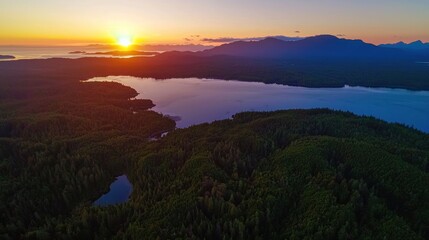 Aerial view of a vibrant sunset over a tranquil lake surrounded by lush forests and mountains