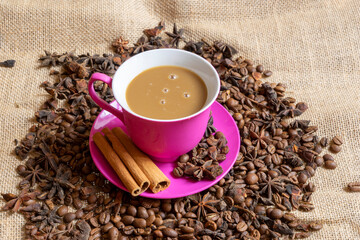 Red cup and saucer with coffee and coffee beans on a brown rag background.