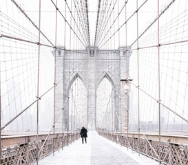 back of person walking on snow covered Brooklyn bridge New York, USA: