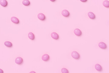 Pink easter dragee on a pink background. Sweet candies in the shape of eggs covered with pink glaze