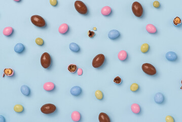 Blue and pink easter dragee on a blue background. Sweet candies in the shape of eggs covered with blue and pink glaze