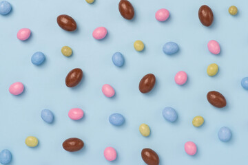 Blue and pink easter dragee on a blue background. Sweet candies in the shape of eggs covered with blue and pink glaze