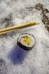Una pieza de Sushi y unos palillos .