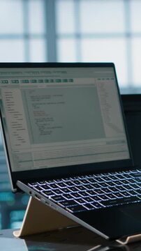 Vertical video Engineer in data center with laptop automating routine maintenance tasks, executing diagnostic scripts. Man coding on notebook, adjusting power settings, validating server
