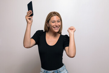 Excited blonde woman smiling, holding her phone