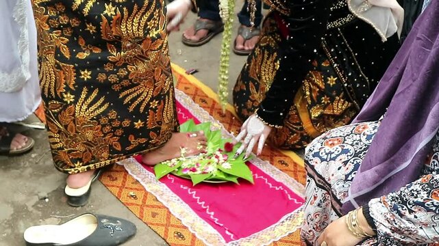 The traditional Javanese wedding procession called "Temu Manten". The bride washes the groom's feet with water mixed flowers. Sacred event of traditions of Indonesian wedding rituals