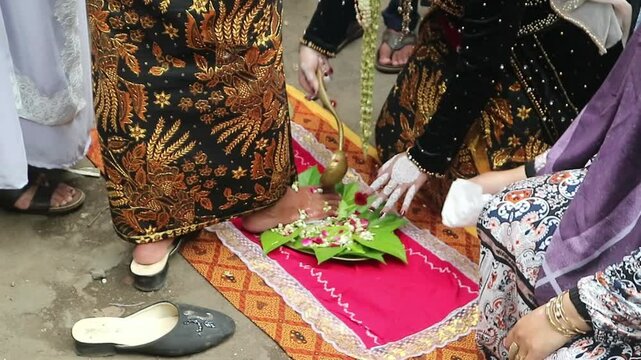 The traditional Javanese wedding procession called "Temu Manten". The bride washes the groom's feet with water mixed flowers. Sacred event of traditions of Indonesian wedding rituals