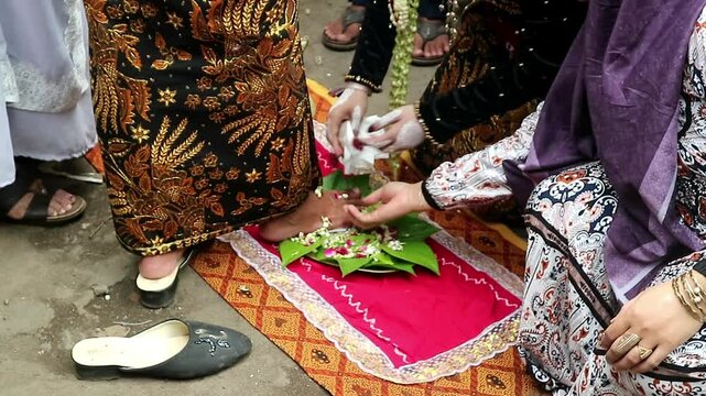The traditional Javanese wedding procession called "Temu Manten". The bride washes the groom's feet with water mixed flowers. Sacred event of traditions of Indonesian wedding rituals
