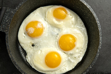 Simple breakfast: four fried eggs cooked sunny-side up in a cast iron skillet. Delicious and ready to eat! Perfect for food illustrations