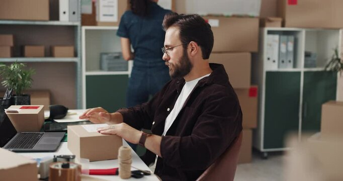 Small business, entrepreneur and man with box, order and laptop for printing of shipping label and ecommerce. Logistics, supply chain and people in startup with stock, online or planning for delivery