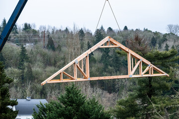 New home under construction in framing phase, roof trusses being delivered and hoisted up to roof...