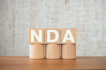 There is wood cube with the word NDA. It is an abbreviation for Mutual Non-Disclosure Agreement as...