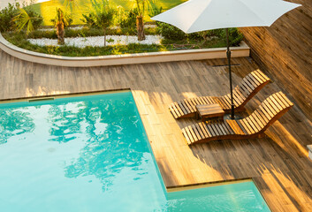 Stylish poolside wooden deck with curved lounge chairs, umbrella, and turquoise pool in a serene...