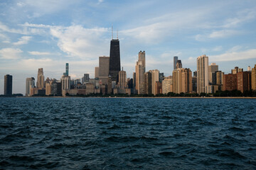 Naklejka premium Chicago skyline with John Hancock Center, view from Lake Michigan, modern skyscrapers, waterfront cityscape, deep blue water, urban architecture, famous landmark, iconic downtown skyline