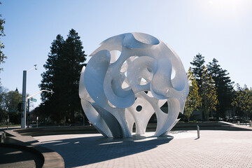 Abstract art sculpture with intricate swirling forms and perforated metal surface paterns. This...