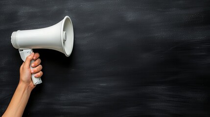 A hand holding a megaphone against a textured black background, symbolizing communication and alertness.