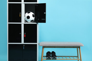Open locker with soccer ball, bench and sneakers on light blue background