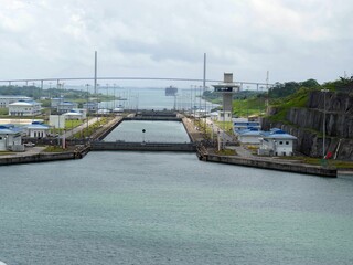 Panama canal locks opening with the centennial bridge in the background, showcasing the impact of...