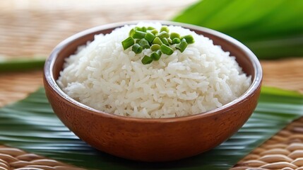 Bowl of fluffy white rice garnished with green onions, served on a banana leaf.