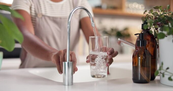 Person, hands and tap water in glass with thirst, hydration and healthy skin detox at home. Woman, open faucet and cup in kitchen for drink, fresh beverage and filtration system at sink for nutrition