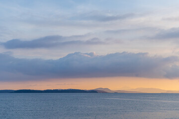 Fototapeta premium Tranquil Ocean Sunset With Cloudy Sky and Distant Islands in View