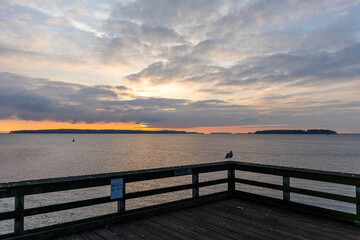 Obraz premium Scenic Sunset Over Calm Waters and Wooden Pier in Coastal Location