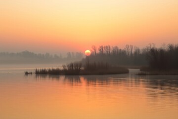 Obraz premium Peaceful scene of a golden sunset over still waters, with reflections and tranquil surroundings