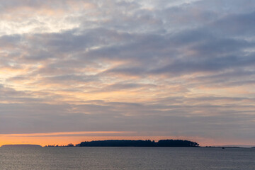 Beautiful Sunset Over Calm Ocean Waters with Distant Forested Island Scene