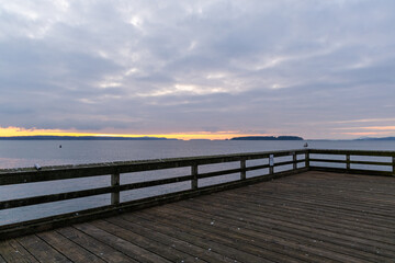 Obraz premium Scenic Sunset View from a Wooden Seaside Pier Over Tranquil Ocean Waves