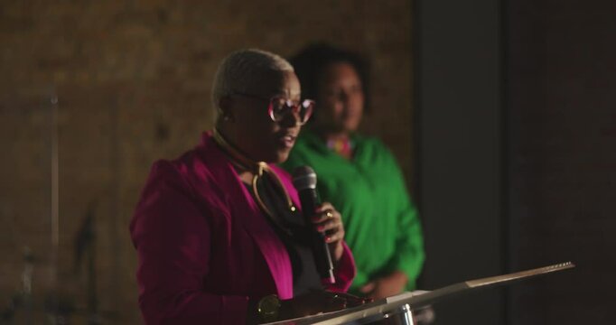 African descent woman preaching passionately during evangelical church gathering, holding microphone, delivering powerful sermon, spiritual guidance to congregation